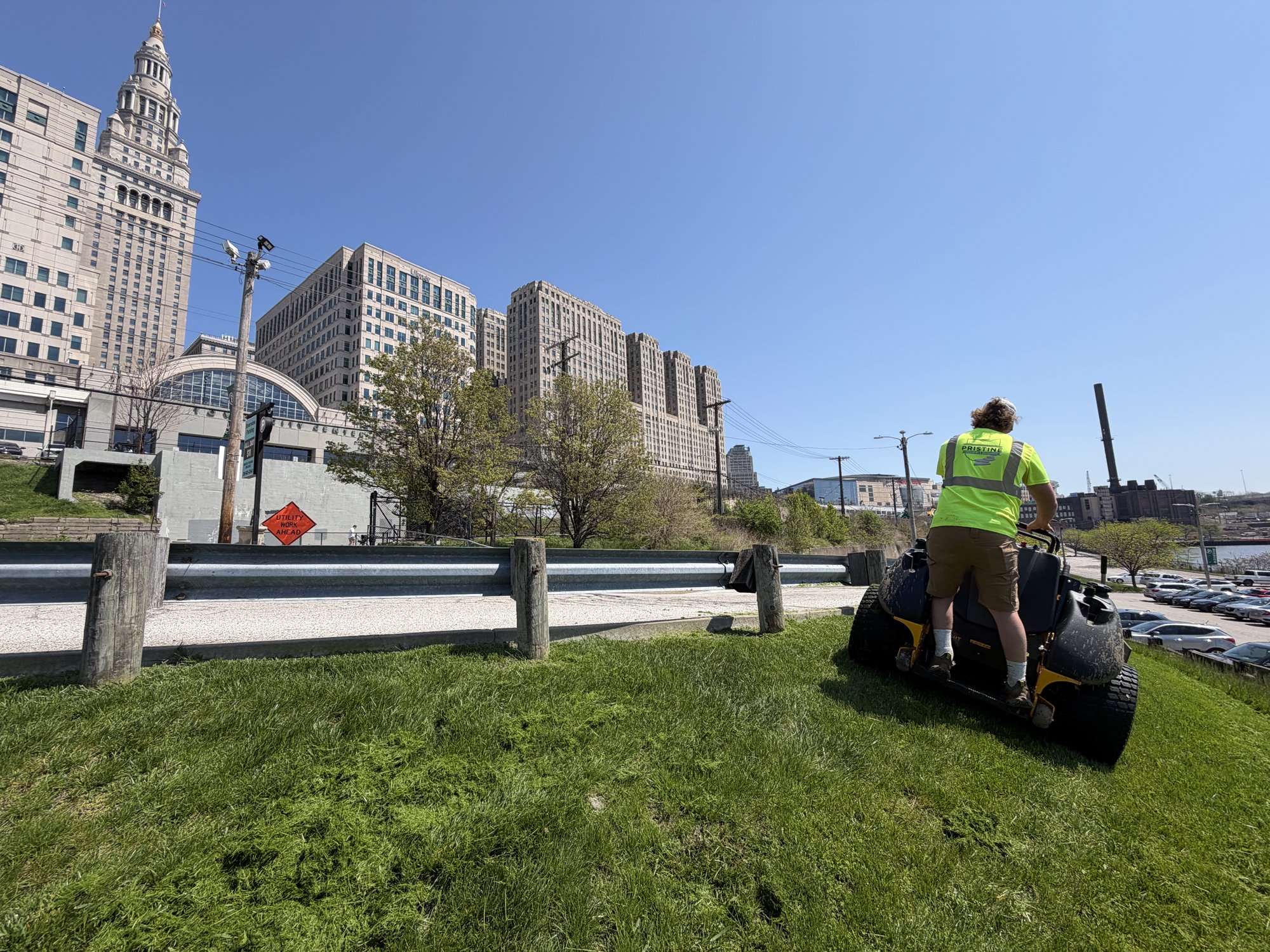 Crew mowing commercial grounds with downtown Cleveland skyline behind