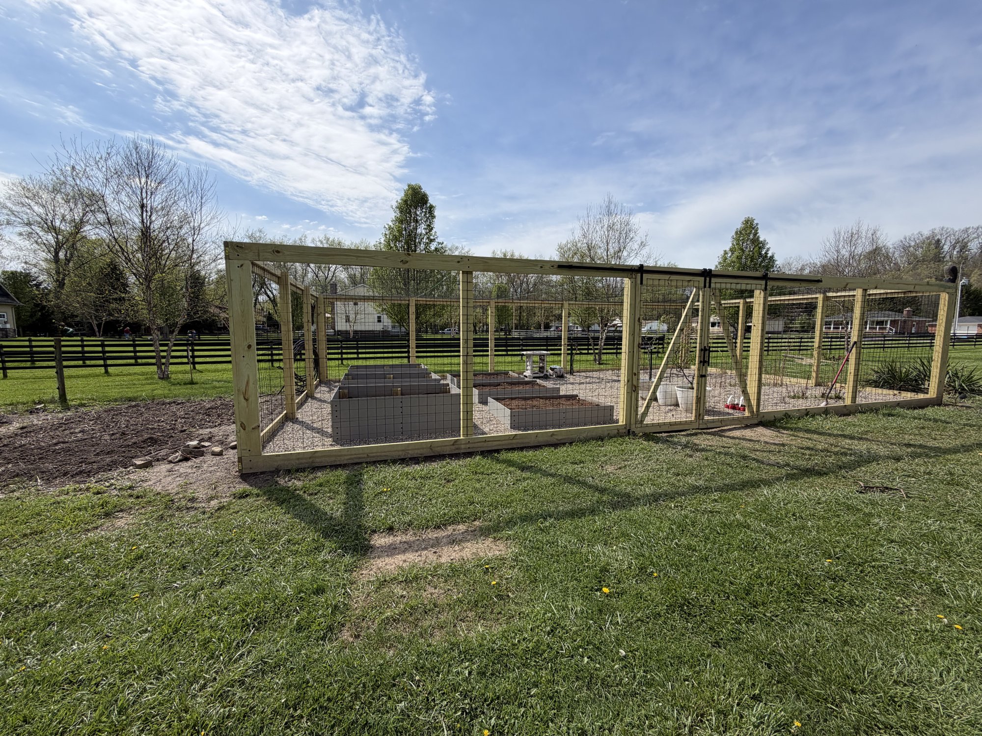 Custom fenced garden enclosure with raised beds and sliding barn doors