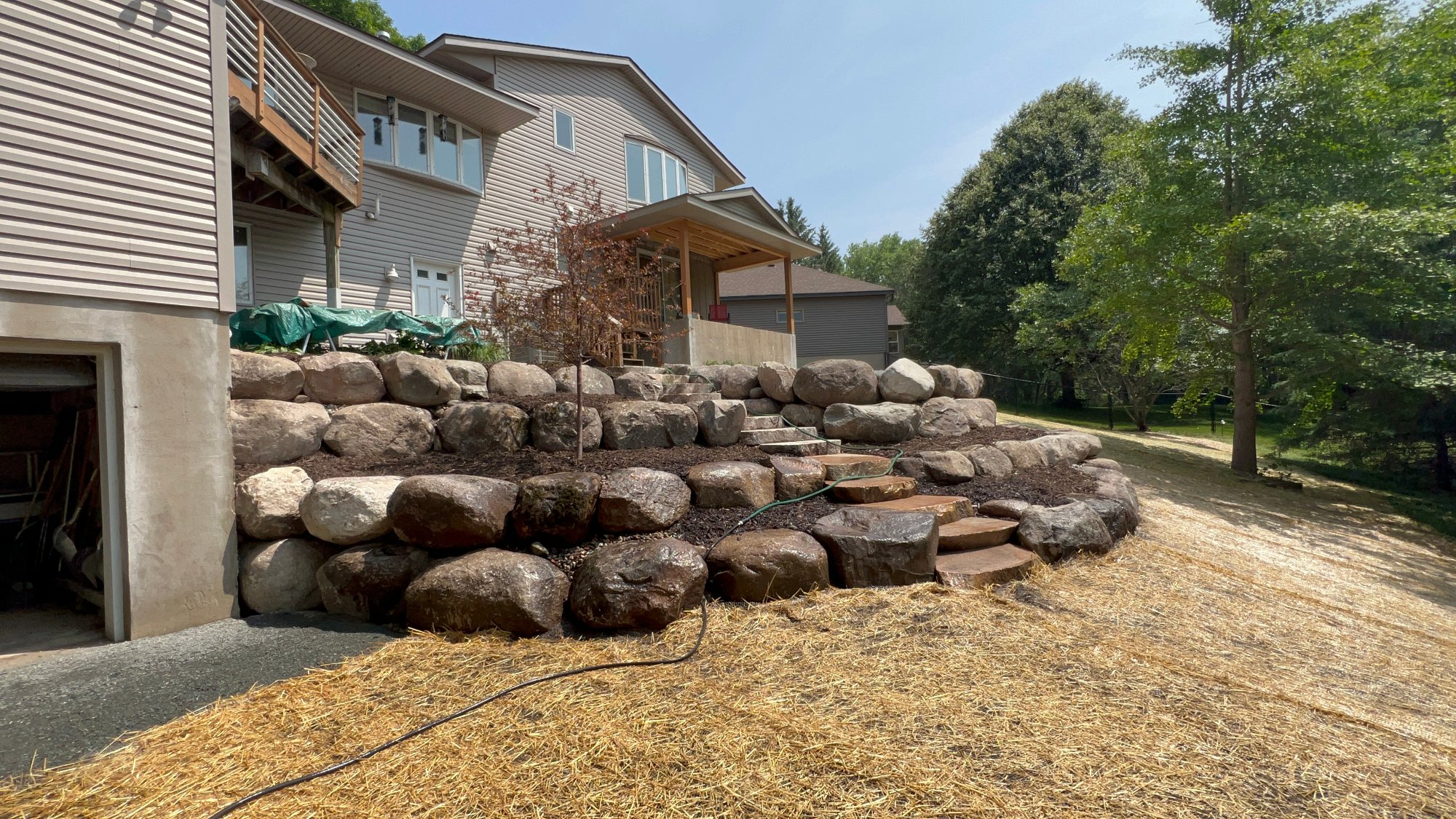 Boulder retaining wall with layered stone