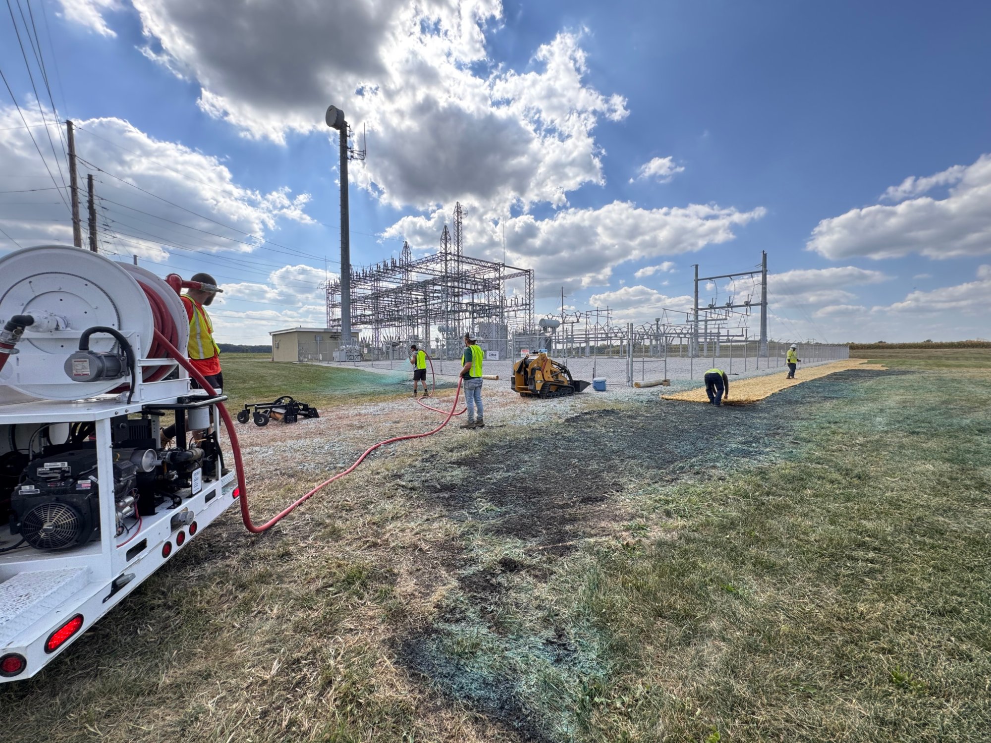 Crew in safety vests laying gravel at an electrical substation site