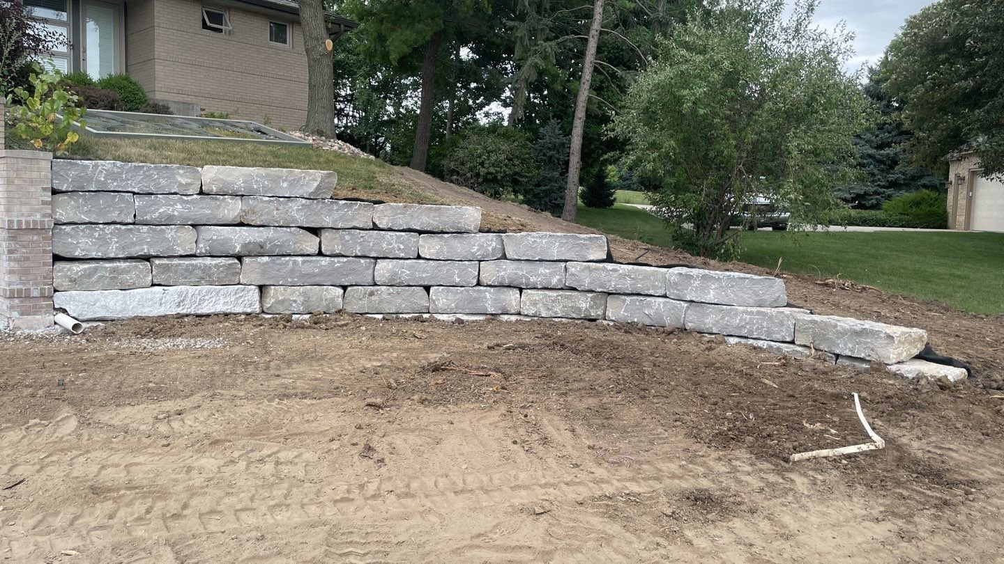 Large block retaining wall stabilizing a sloped yard