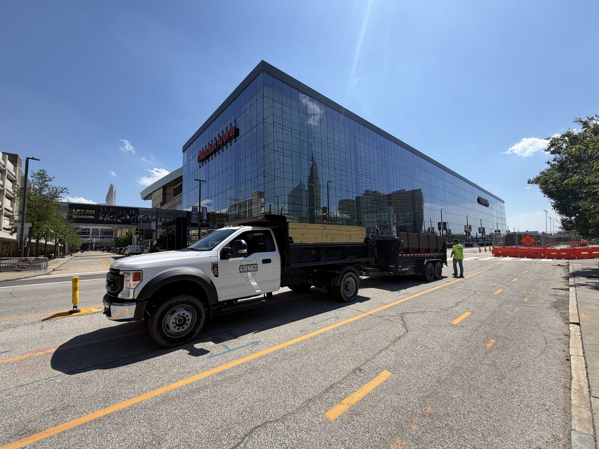 Pristine Landscaping branded dump truck and trailer on site in downtown Cleveland